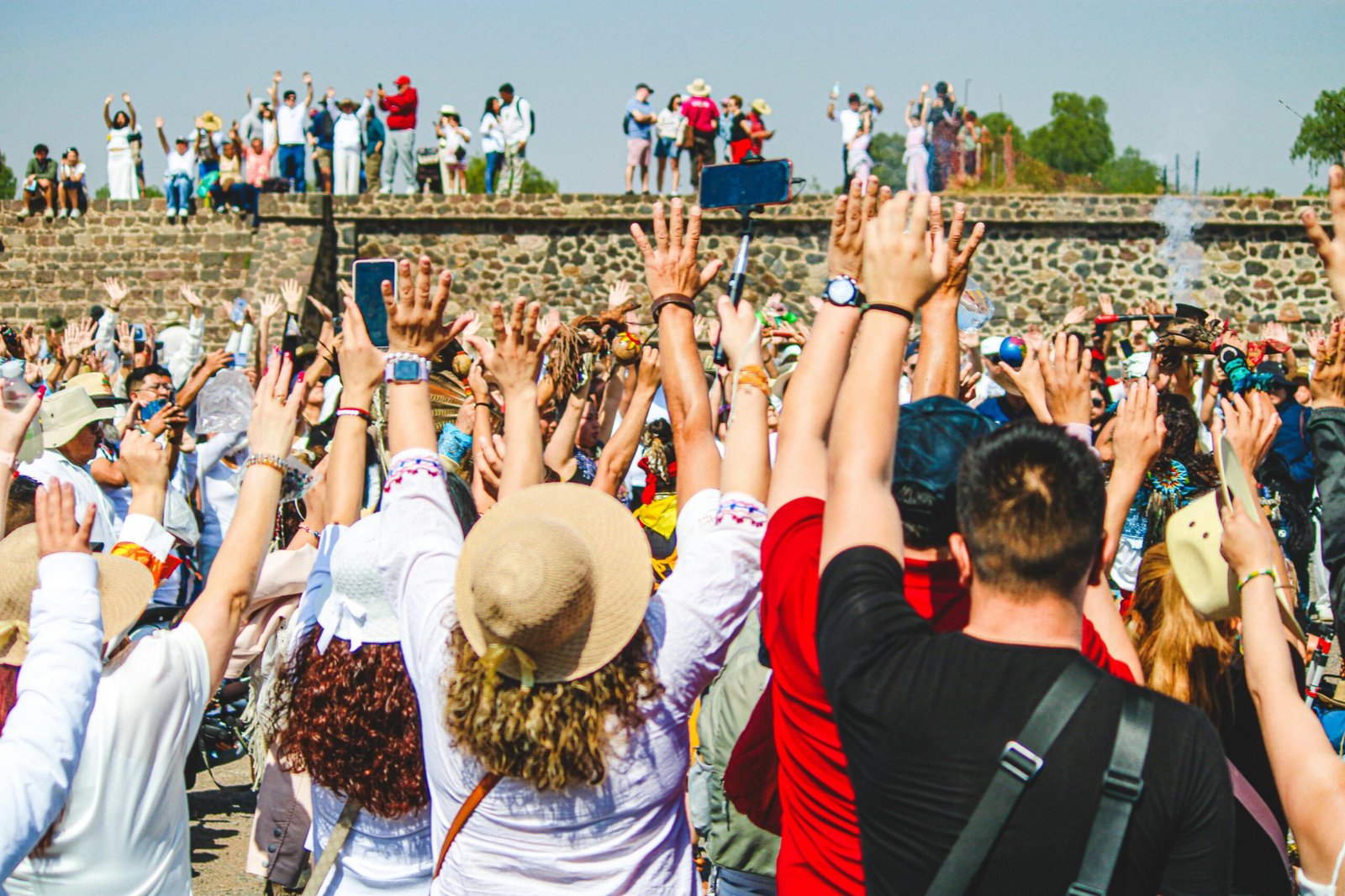 A lively crowd raising hands in celebration at Teotihuacán, Mexico, capturing rich cultural ambiance.